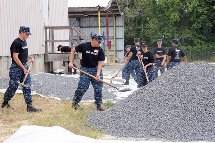 Sailors from Naval Nuclear Power Training Command at Naval Weapons Station Charleston, pile gravel on a tarp to stop weed growth at the local non-profit, Habitat for Humanity Restore in Goose Creek, as part of the Day of Caring community service event.(U.S. Navy photo by Mass Communication Specialist 1st Class Jennifer R. Hudson)