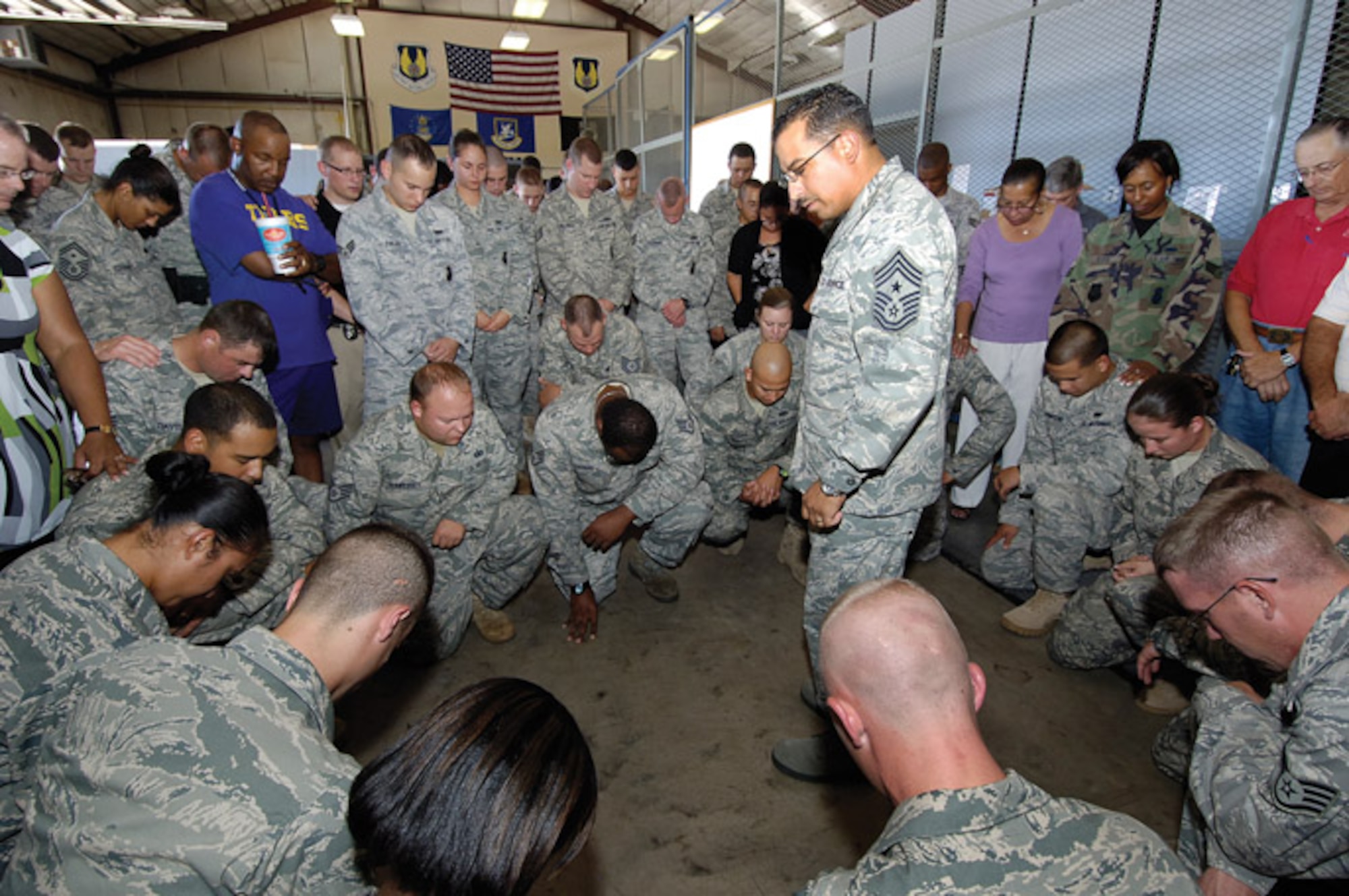 Members of the 72nd Security Forces Squadron preparing to deploy are encircled by friends, family and co-workers during a prayer offered Sept. 2 by Oklahoma City Air Logistics Center Command Chief Master Sgt. Kevin Vegas.  (Air Force photo by Margo Wright)

