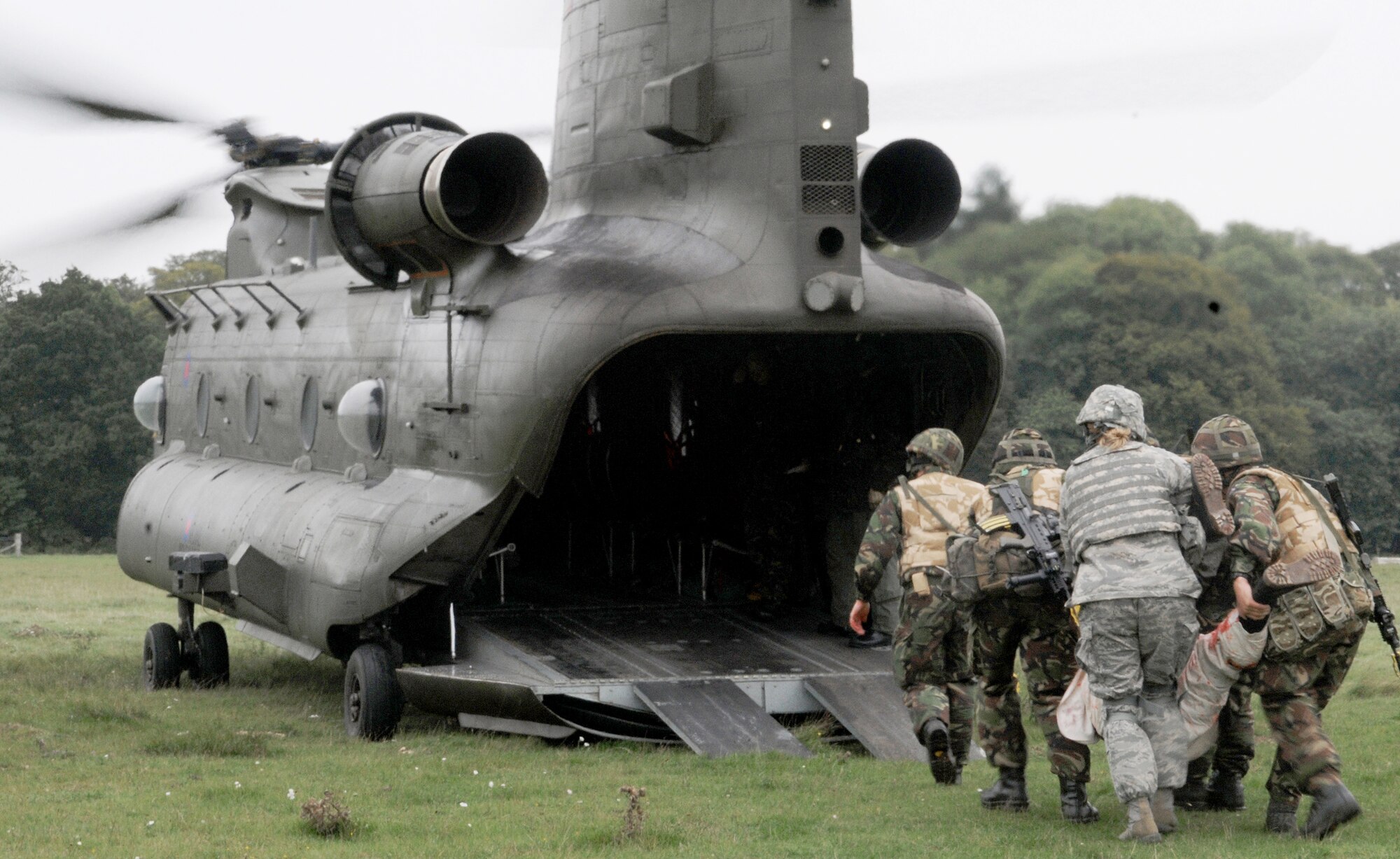 Members of the Royal Air Force Regiment and Tech. Sgt. Tisha Bate carry a "patient" into an RAF Chinook as part of a mass casualty training scenario Sept. 8, 2010, at Stanford Training Area, England. The regiment flight was conducting its last training scenarios before deploying to Afghanistan. U.S. Airmen embedded into the training to fill the place of U.S. Marines the British force would be working side by side with on their deployment. Sergeant Bate is assigned to the 100th Security Forces Squadron at Royal Air Force Mildenhall, England. (U.S. Air Force photo/Staff Sgt. Thomas Trower) 