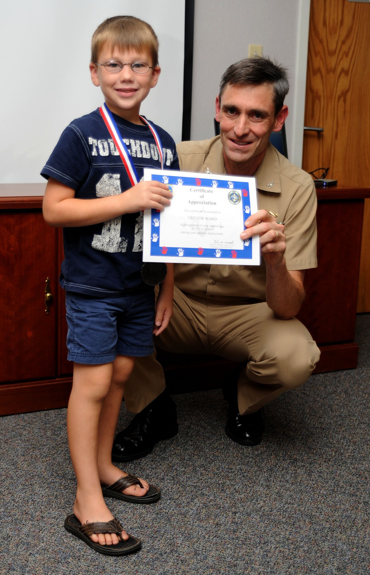 Trevor Ward receives a certificate from U.S. Navy Capt. Ralph Ward during the Little Heroes ceremony at the Airmen and Family Readiness Center on Joint Base Charleston, S.C., Sept. 14, 2010. The ceremony recognized the children of Team Charleston who have recently experienced a parent deploying or have a parent who is still deployed. Following the ceremony, the children took part in a reception which included socializing and snacks. Captain Ward is the Naval Weapons Station commander and Trevor is the son of Staff Sgt. Daniel Ward who is an aerospace ground equipment technician with the 437th Maintenance Squadron. (U.S. Air Force Photo/Airman 1st Class Lauren Main) 
