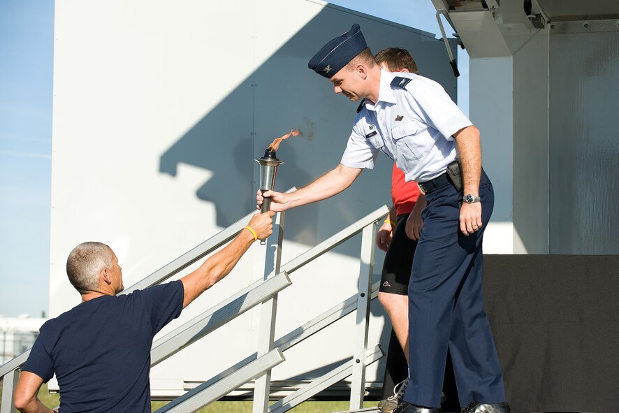 (Right) Col. Manson Morris, 436th Airlift Wing commander, passes the Special Olympics torch to Mark Wise, Special Olympics of Delaware director of training and volunteer management, Sept. 11, 2010. The torch represents a year-long effort by Delaware's law enforcement community to support the Special Olympics by providing volunteers, public awareness adn needed financial support.(U.S. Air Force photo by Jason Minto/Released)