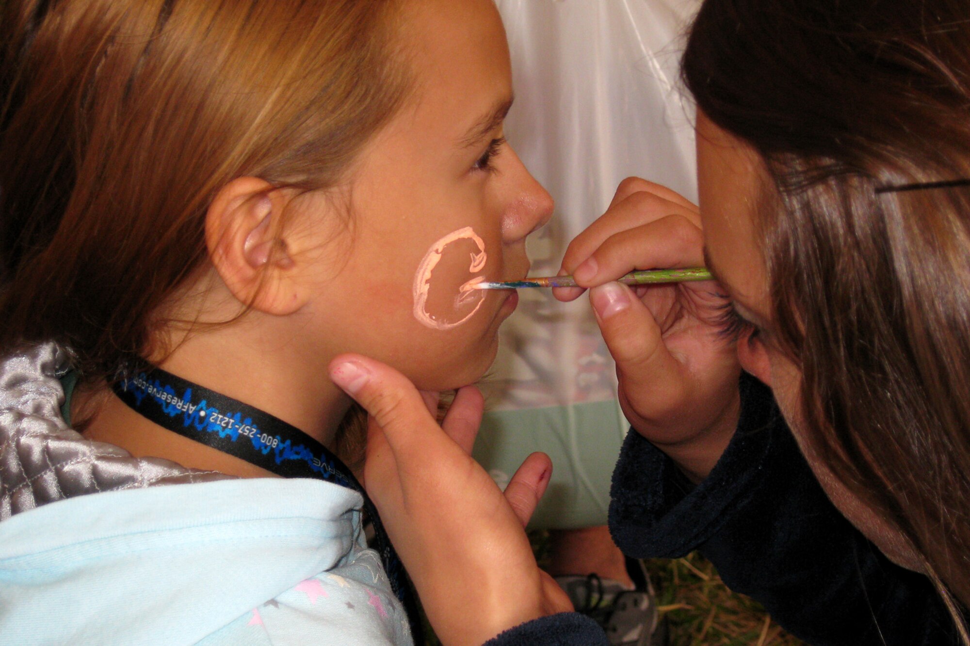 GRISSOM AIR RESERVE BASE, Ind. -- Sydney Wick, 10, has a team spirit "G" painted on her face by Taylor Raisor during Grissom's Sept. 11 Family Day picnic. Sydney's brother, Senior Airman Shawn Cherty is a member of the 434th Maintenance Squadron. Ms. Raisor volunteered in the base activities as a member of Logansport High School's Berryettes dance team. (U.S. Air Force photo/Capt. Kelly L. Howard)