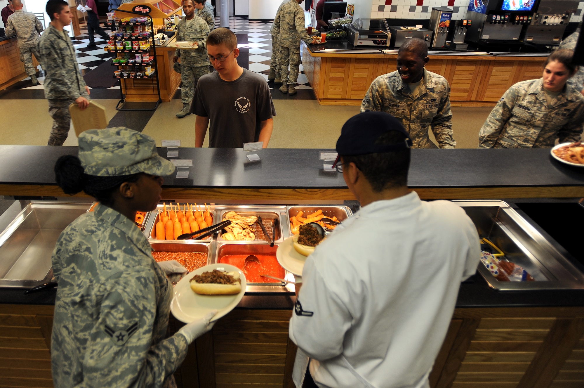 WHITEMAN AIR FORCE BASE, Mo., -- Airman 1st Class Laketha Atkins (left), and Airman Mario Connell, serve Airmen food from the short-order line during midday chow, Sept. 13. The 509th Force Support Squadron, Food Services technicians, operate with more than 400 recipes and prepare food for nearly 3,500 Airmen each week.  (U.S. Air Force photo by Senior Airman Kenny Holston)(Released)

