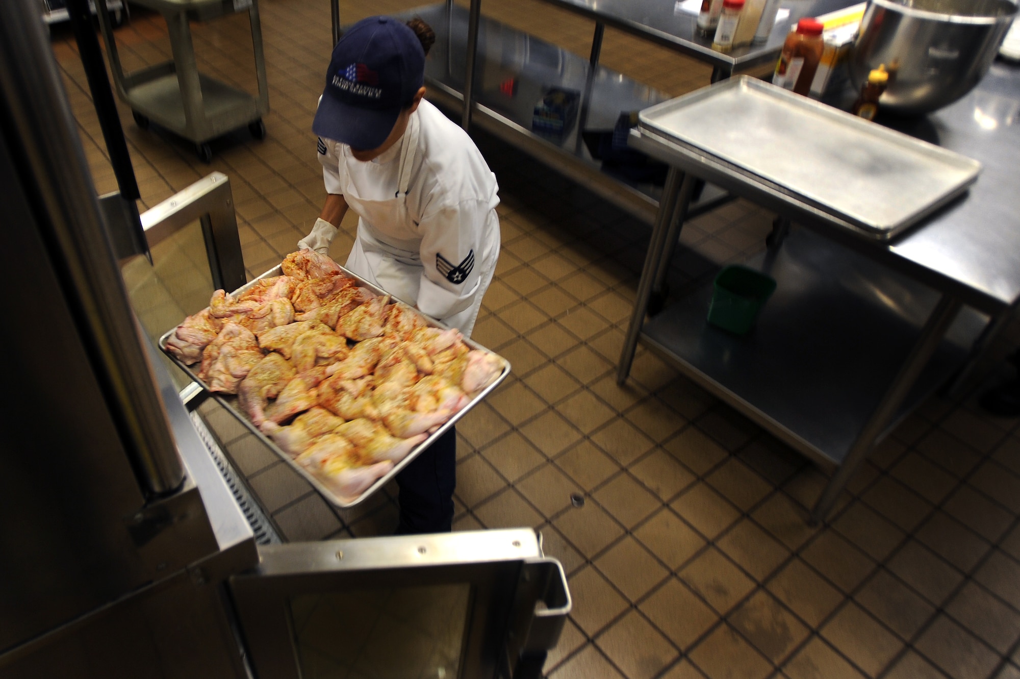 WHITEMAN AIR FORCE BASE, Mo., -- Senior Airman Erica Stanton, 509th Force Support Squadron, Food Services technician, places chicken in an oven to bake in preparation for midday chow at the Whiteman dining facility, Sept. 13. The 509th FSS Airmen operate with more than 400 recipes and prepare food for nearly 3,500 Airmen each week. (U.S. Air Force photo by Senior Airman Kenny Holston)(Released)

