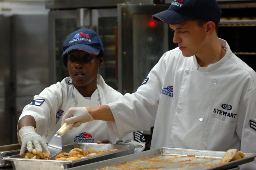 WHITEMAN AIR FORCE BASE, Mo., -- Staff Sgt. Shaundria Brentley (left) and Airman 1st Class Justin Stewart, 509th Force Support Squadron, Food Services technicians, place stuffed fish into a pan in preparation for midday chow at the Whiteman dining facility, Sept. 13. The 509th FSS Airmen operate with more than 400 recipes and prepare food for nearly 3,500 Airmen each week.  (U.S. Air Force photo by Senior Airman Kenny Holston)(Released)


