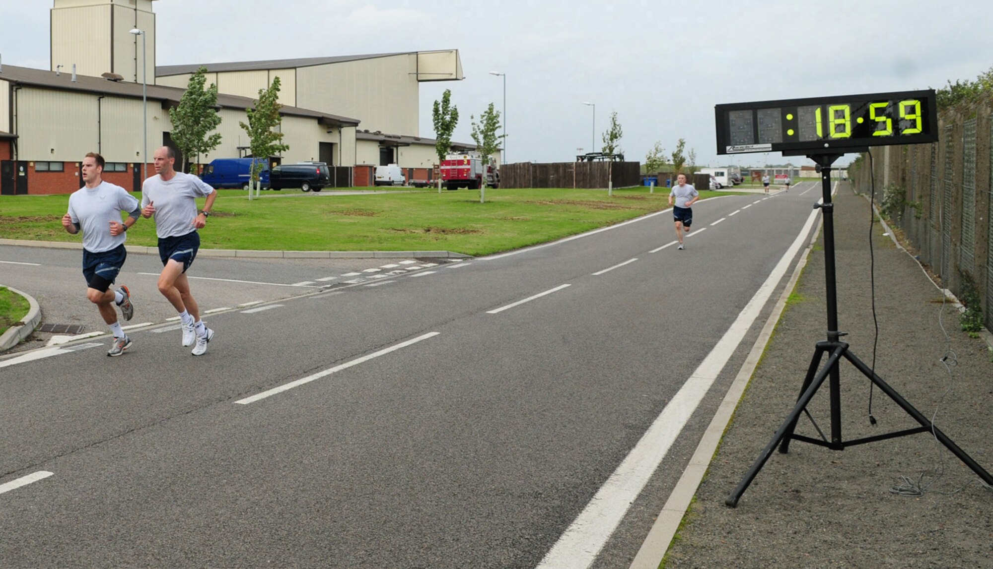 RAF MILDENHALL, England -- Capt. Jordan Kemp, left, 351st Air Refueling Squadron, and Maj. David Wieland, 100th Air Refueling Wing, cross the finish line together in first place, at the 100th ARW 5K run Sept. 10 on the south side of base. The run is held monthly to encourage fitness and camaraderie. (U.S. Air Force photo/Karen Abeyasekere)