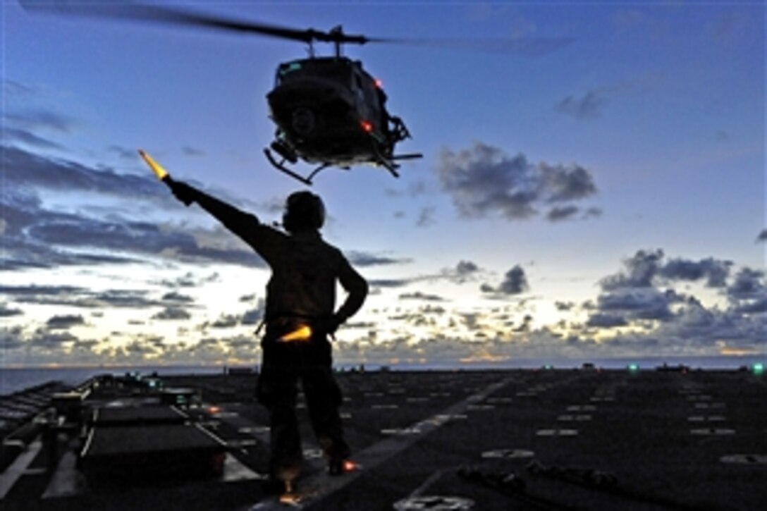 U.S. Navy Petty Officer 3rd Class Lanh Dinh directs a UH-IN Huey helicopter during takeoff from the amphibious dock landing ship USS Harpers Ferry in the Philippine Sea, Sept. 14, 2010. The Harpers Ferry is on patrol in the western Pacific Ocean, and is part of the permanently forward-deployed Essex Amphibious Ready Group participating in Valiant Shield 2010.