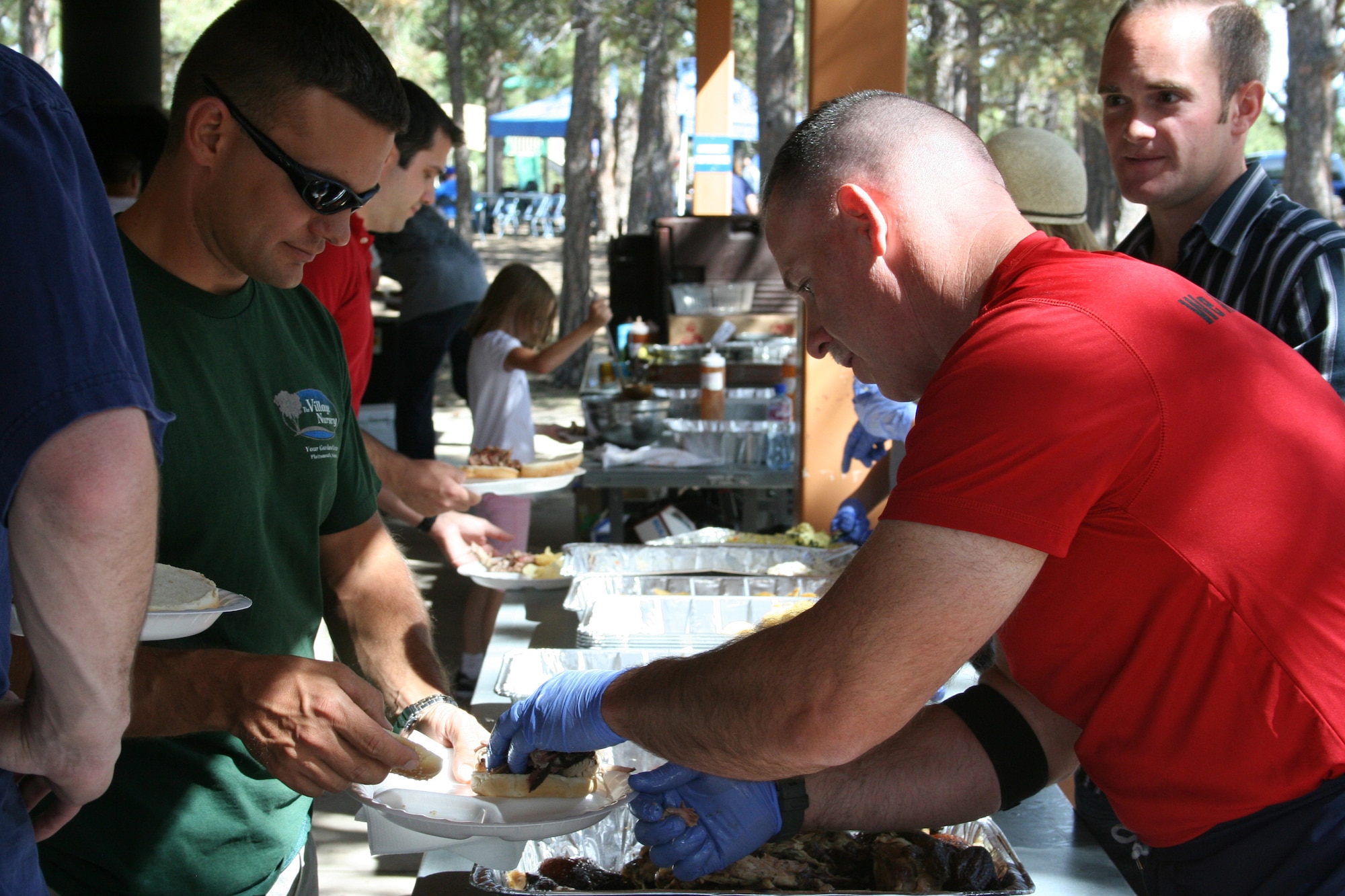 Chief Master Sgt. Rocky Hart (right) threw on the gloves and helped serve lunch from The Firehouse to Maj. Darin Durand  Sept. 12 at the 310th Space Wing?s southern units family day. This year?s family day was held at the Air Force Academy?s FamCamp.  (U.S. Air Force Photo/ Staff Sgt. Desiree Economides)
