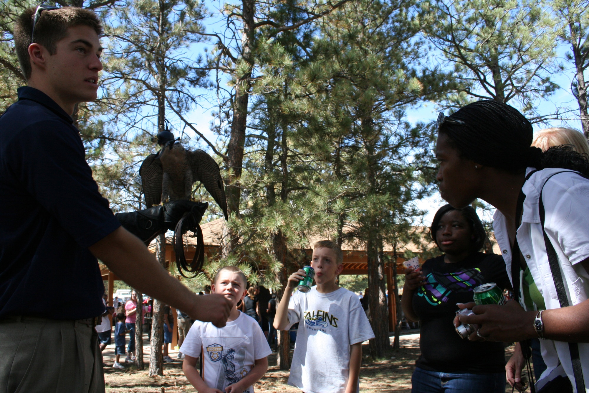 Cameron, an Air Force Academy falconer, holds one of the birds of prey and talks to 310th Space Wing family members about the falconer program, Sept. 12 at the 310SW?s southern units family day picnic. Various organizations from the U.S. Air Force Academy and the 310SW contributed to the success of this year?s picnic. (U.S. Air Force Photo/ Staff Sgt. Desiree Economides)