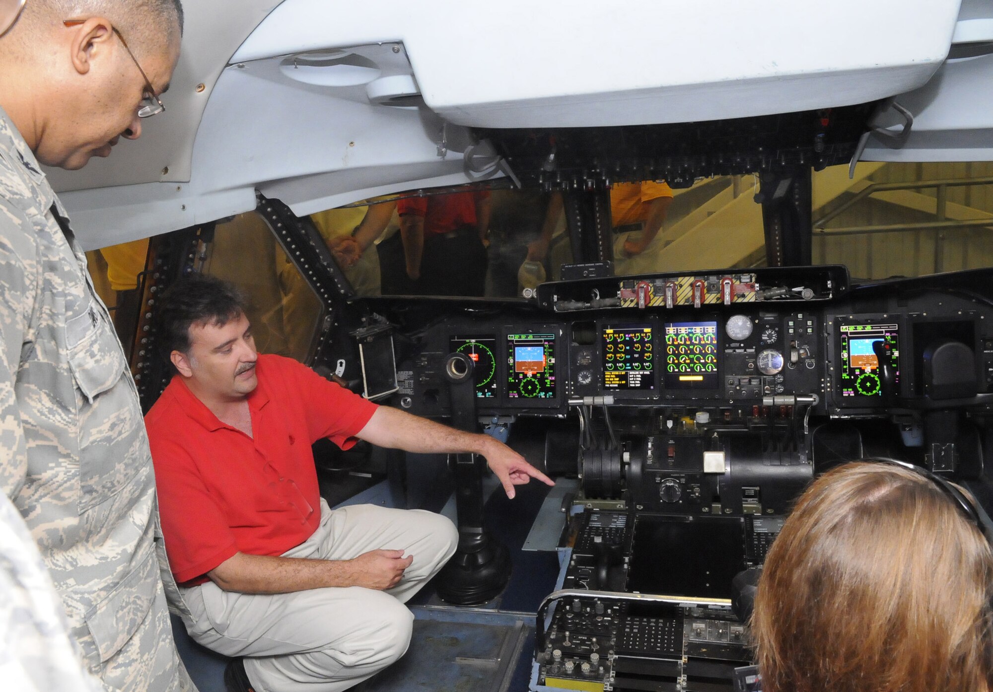 Todd Morris, bottom left, talks about the C-5 cockpit with ceremony attendees. Using the cockpit will allow engineers a way to test software in a real environment without tying up actual C-5s. U. S. Air Force photo by Sue Sapp
