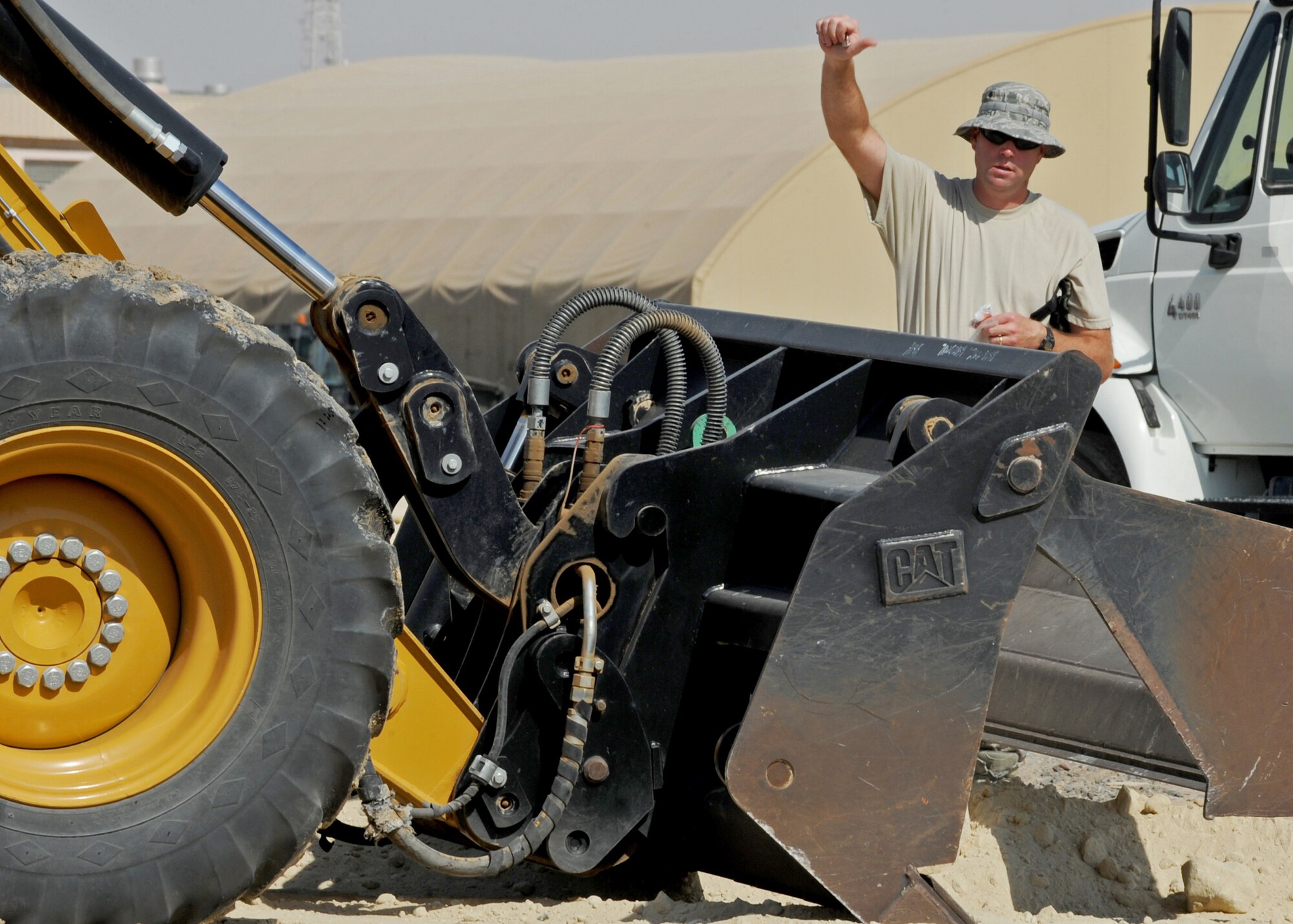 SOUTHWEST ASIA - Master Sgt. Jeffrey Roberts of the 386th Expeditionary Civil Engineer Squadron guides a bulldozer while its operator removes rocks from the sand in preparation for laying asphalt at an undisclosed air base here Sept. 8, 2010. (U.S. Air Force photo by Senior Airman Laura Turner)