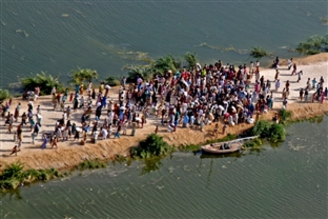 An aerial view of Pakistani flood survivors isolated on a road surrounded by water as a U.S. CH-53E Sea Stallion helicopter crew begins their departure after dropping off food in support of the Pakistan flood relief effort in Pano Aqil, Pakistan, Sept. 14, 2010. The CH-53E crew is assigned to the 26th Marine Expeditionary Unit.