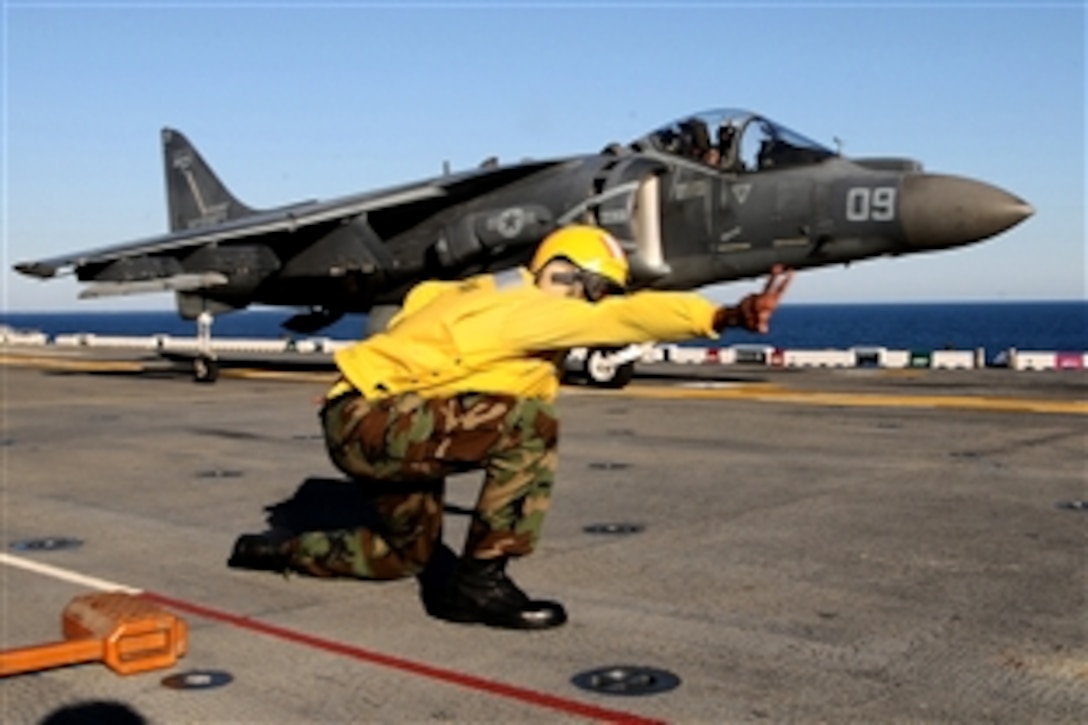 U.S. Navy Petty Officer 1st Class Rodrickus Shepherd signals an AV-8B Harrier aircraft pilot to launch from the USS Bataan in the Atlantic Ocean, Sept. 14, 2010. The pilot is assigned to the Marine Attack Squadron 233.