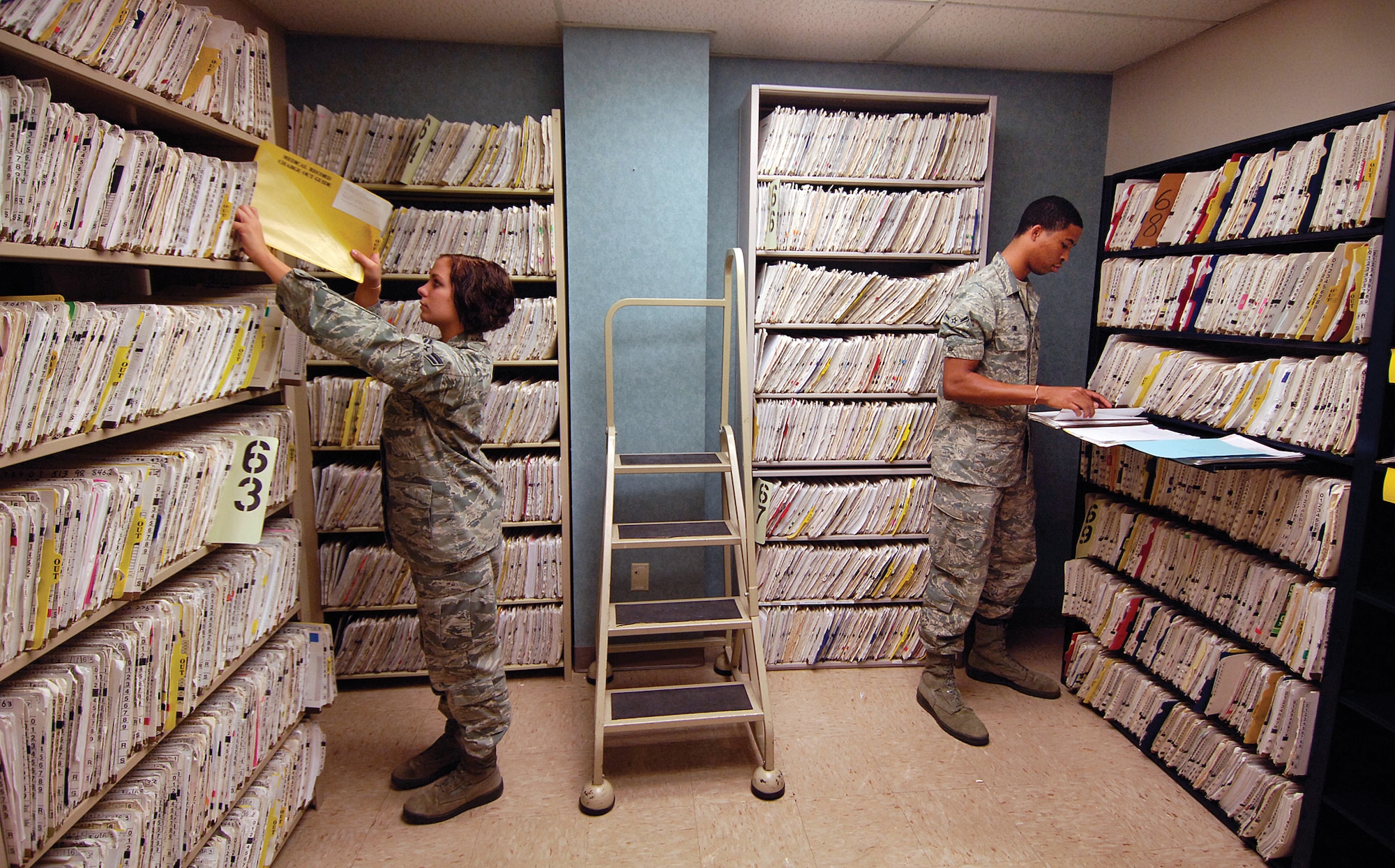 Airman 1st Class Stephanie Butzer and Airman Justin Ginn are surrounded by medical records in one of several rooms of the 72nd Medical Group’s  Outpatient Records Section. Decreased manning necessitated decentralizing the record system and reverting to a centralized system. Technicians are filing new records and approximately a foot-high worth of existing records each day to complete the move.  “The mission for getting it done quickly is to serve our patients quickly and efficiently,” said Staff Sgt. Roslyn Evans, non-commissioned officer in charge of Outpatient Records.  (Air Force photo by Margo Wright)