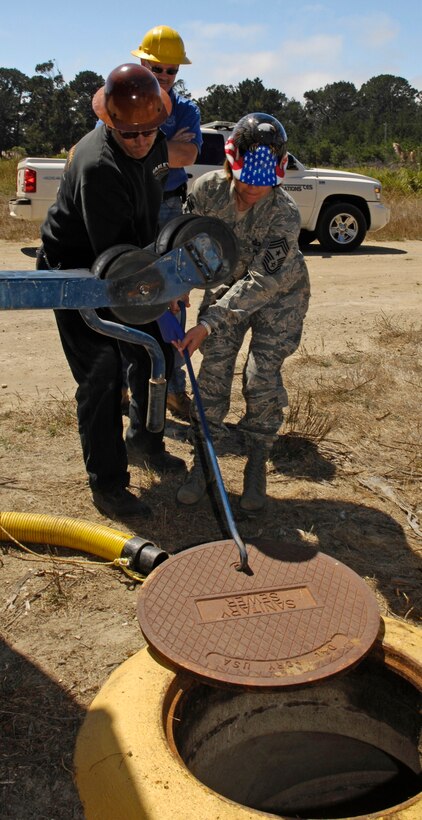 VANDENBERG AIR FORCE BASE, Calif. - Revealing Vandenberg's underground, Chief Master Sgt. Angelica Johnson, 30th Space Wing command chief, helps pull back a sewage manhole cover at Cocheo Park here Thursday, Aug. 26, 2010. Col. Richard Boltz, 30th Space Wing commander, and Chief Johnson have been partaking in monthly activities within Team V's work centers focusing on some of the dirtiest jobs at Vandenberg. This month's focus was on the 30th Civil Engineer Squadron's Operations Flight. (U.S. Air Force photo/Airman 1st Class Lael Huss)
