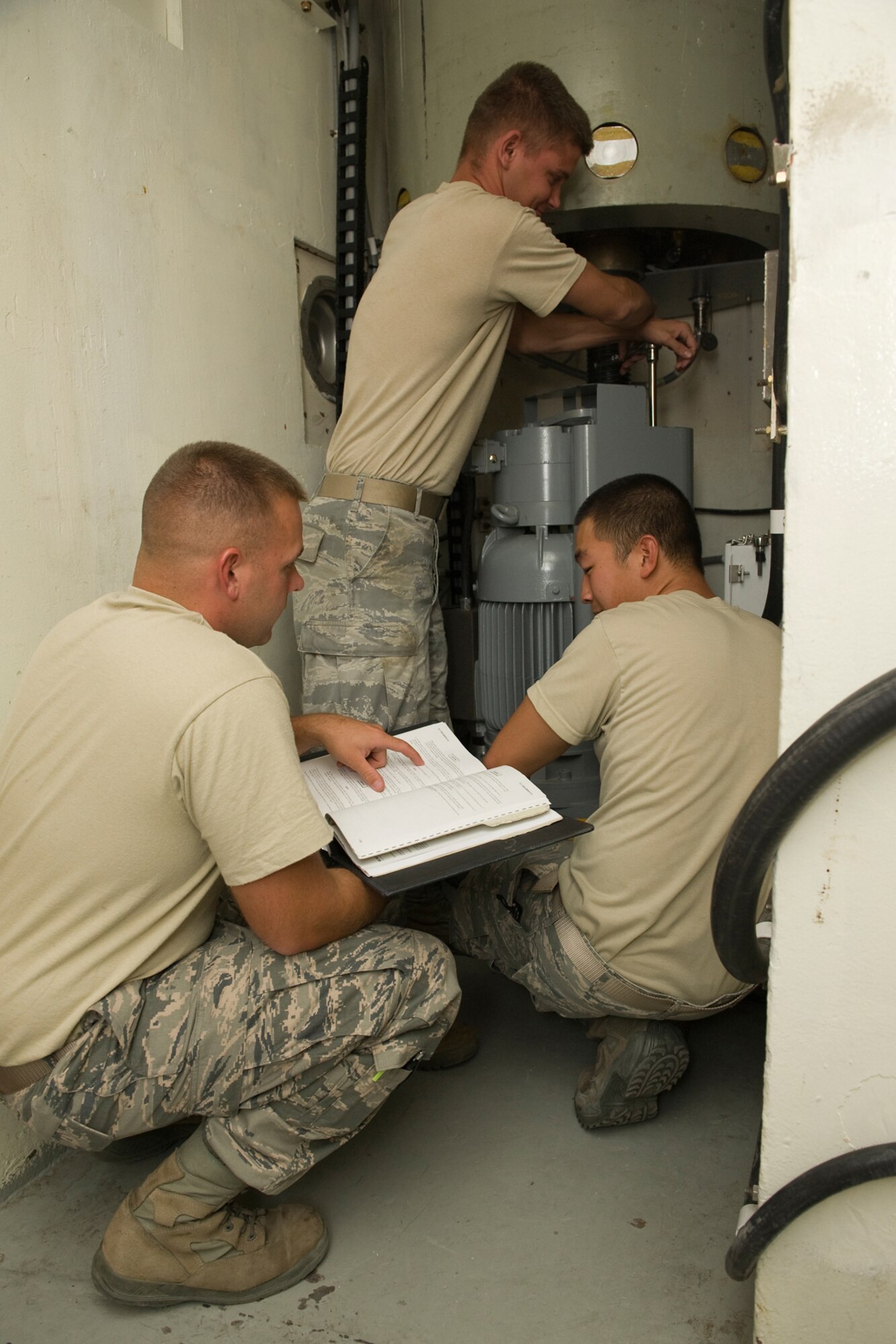 Staff Sgt. Shawn Scrivener, Electro-Mechanical Team Chief, reads from the Technical Order, while Senior Airmen James Kirby (standing) and Nicholas Nam work together to troubleshoot a problem during training for the upcoming Global Strike Challenge competition Sept. 20-24. (U.S. Air Force photo/Beau Wade)