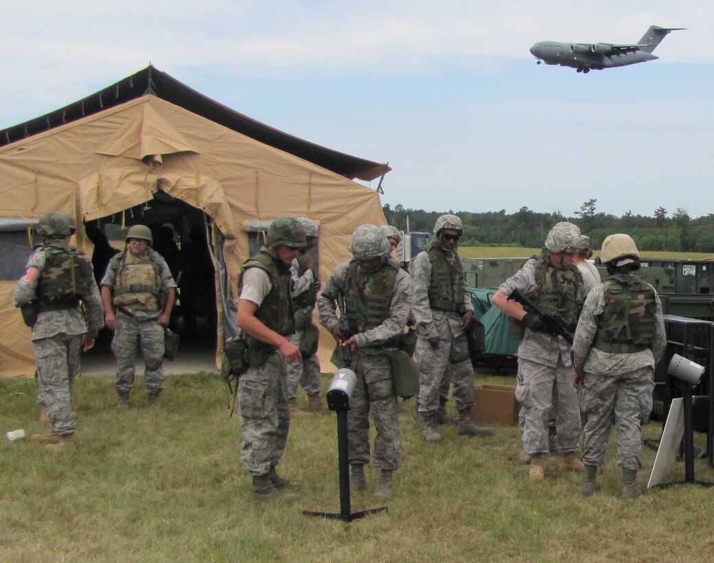 Members of the 560th RED HORSE Squadron are issued M-4 Carbines as a C-17 Globemaster III approaches for landing during their annual field training exercise Sept. 10-13, 2010 at North Auxiliary Air Field S.C. (U.S. Air Force photo/Tech. Sgt. Steve Wells)