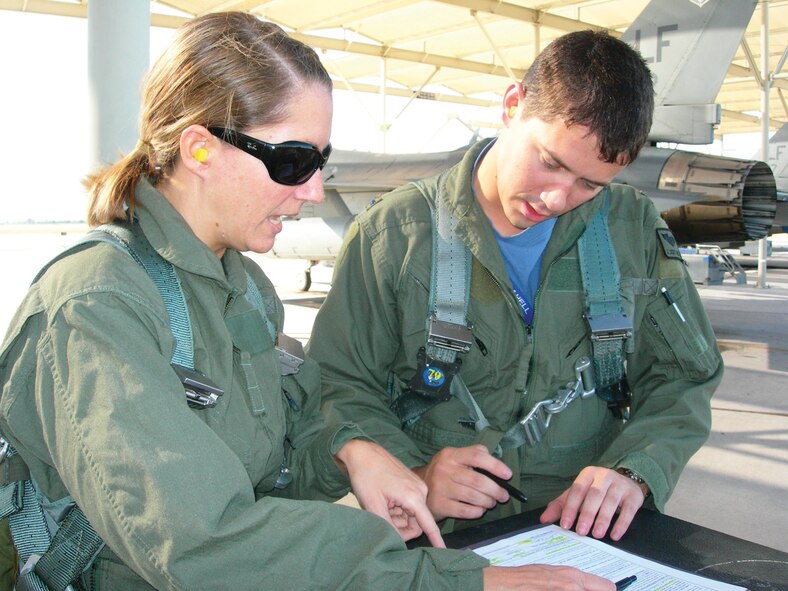 Tech. Sgt. Erin Caldwell, 56th Fighter Wing command section NCO-in-charge, signs re-enlistment paperwork on the Luke flightline with 1st Lt. Scott Marlin, 309th Fighter Squadron student pilot.  Lieutenant Martin re-enlisted Sergeant Caldwell in the air using radio communications between aircraft during an incentive flight September 10th. (Courtesy photo)