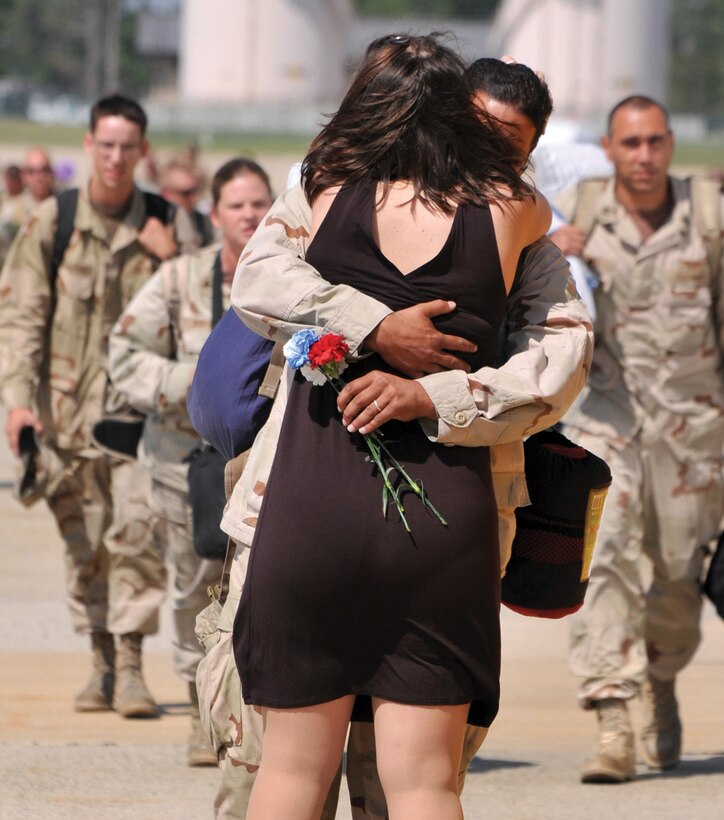Aviation Structural Mechanic 2nd Class Jonathan Kaplan, assigned to Electronic Attack Squadron VAQ-209, receives a hug and kiss from his wife as they were selected to be the 'First Kiss' during a homecoming celebration. (Photo by MC2 (AW) (SW) Clifford L. Davis)