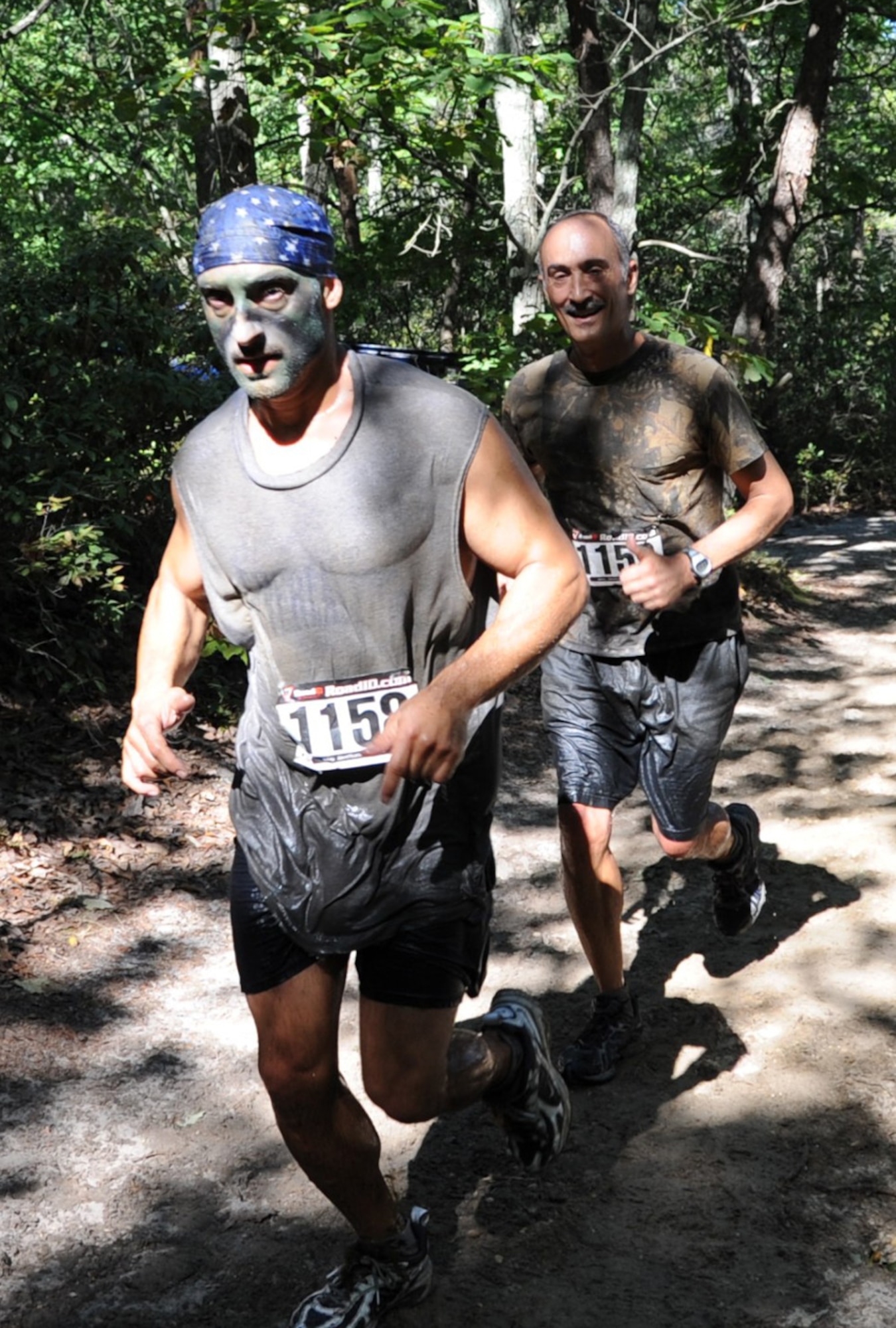 Two participants run through the ‘Hamburger Hill’ tank trail. The annual Mud Run is open to the public and attracts both avid and novice runners, some dressed in elaborate costumes and some with simple team T-shirts. (U.S. Air Force photo/Staff Sgt. Danielle Johnson)