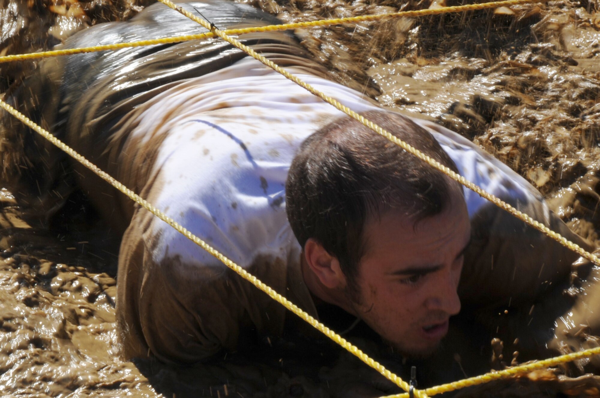 Participant at the "2010 Beast of the East" McGuire Mud Run, stays low and dirty in 'The Low Crawl,' a mud-filled pit 80 feet wide and 60 feet long. (U.S. Air Force photo / Airman 1st Class Dennis Sloan)