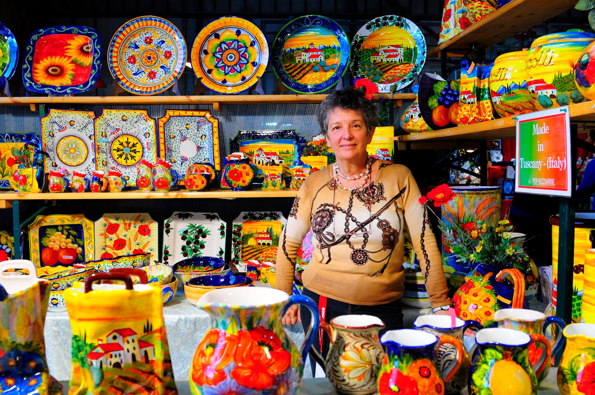 Patrizia Passoni, Pep Bizzarrie pottery store, stands with pottery that she decorated by hand at the Ramstein Welfare Bazaar, Ramstein Air Base, Germany, Sept. 16, 2010. For more than four decades, the Kaiserslautern Military Community has benefited from the Ramstein Welfare Bazaar. This annual event dates back to 1965 and has grown into one of the largest military bazaars in Europe. (U.S. Air Force photo by Airman Kendra Alba)