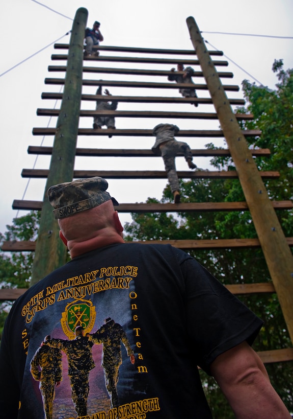 An instructor looks on as U.S. Army soldiers climb up and over a vertical stairway at the obstacle course on Fort Leonard Wood, Mo., during day two of the 14th Annual Warfighter Challenge, Sept. 14, 2010.