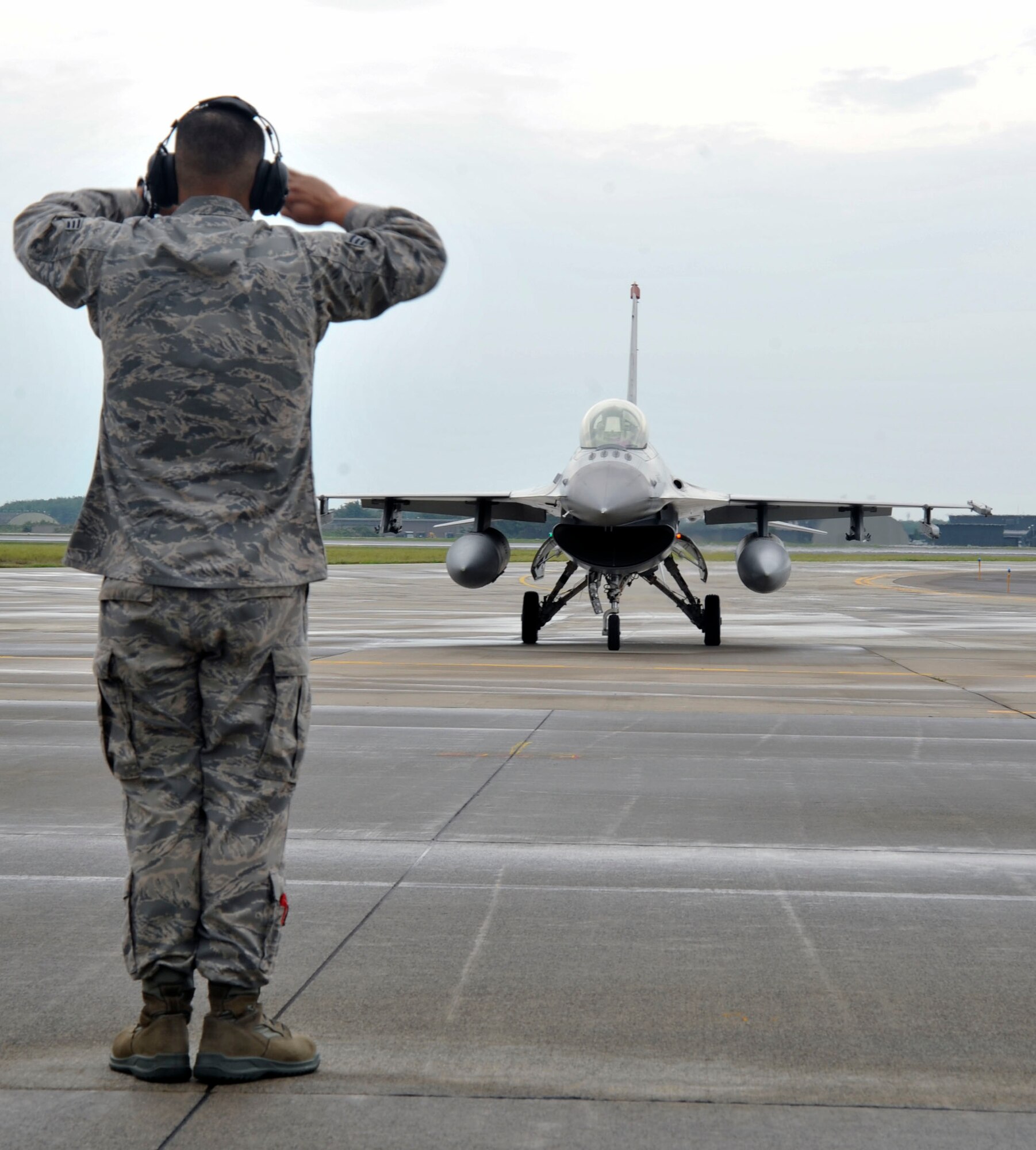 U. S. Air Force Senior Airman Jessie Arenal, 35th Aircraft Maintenance Squadron, marshals an F-16 Fighting Falcon onto the Misawa Air Base, Japan runway following a bi-lateral flyby demonstration performed with a Japan Air Self-Defense Force F-2 aircraft, Sept. 19, 2010. The aircraft performed during the annual Misawa Air Festival, which was hosted by the JASDF. (U.S. Air Force Photo/Tech. Sgt. Russell McBride) (Released)