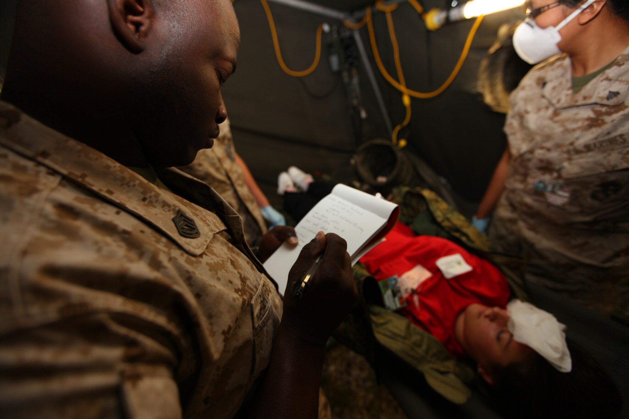 Gunnery Sgt. Octavius Shivers, the non-commissioned officer in charge of Detachment Personnel Retrieval and Processing, Smyrna, Ga., takes notes as his Marines examine a faux corpse Sept. 15 inside the mock PRP collection point set up during the 2010 Medical Training Exercise in Central and Eastern Europe at Danilovgrad Army Base, Montenegro. The exercise challenges approximately 250 military medical personnel from the U.S. and nine central and eastern European nations to respond to a series of simulated disasters by collecting and treating role-player casualties. For more information, go to www.usafe.af.mil/medceur.asp and www.odbrana.gov.me. (U.S. Marine Corps photo/Lance Cpl. Jad Sleiman)