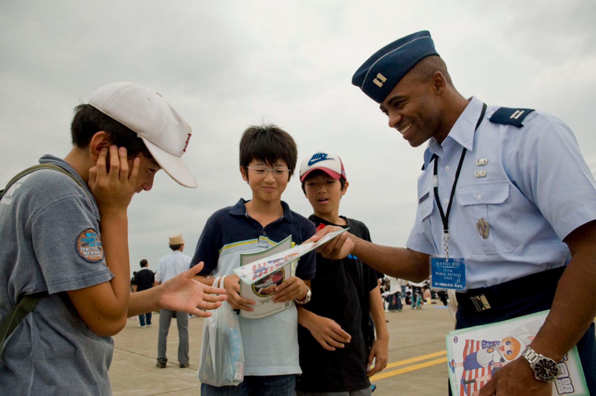 U.S. Air Force Capt. Darrick Lee, 35th Fighter Wing Chief of Public Affairs, distributes manga (Japanese comics) to children attending the base air festival, Sept. 19, 2010, at Misawa Air Base, Japan. This year marks the 50th anniversary of the Treaty of Mutual Cooperation and Security between Japan and the United States. (U.S Air Force photo by Senior Airman Jessica Lockoski/Released)