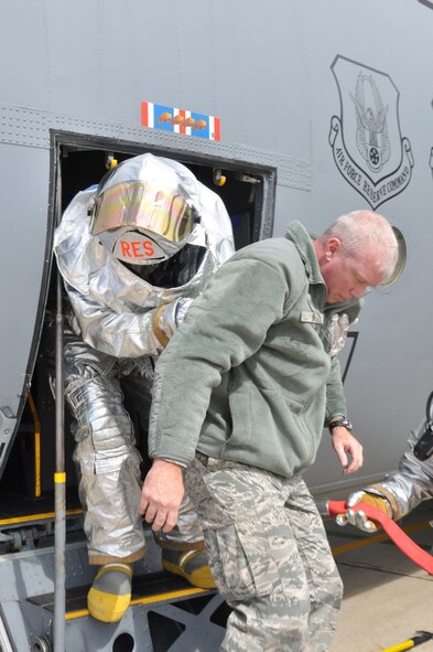 A fire fighter from the 934th Civil Engineer Squadron assists exercise casualty Technical Sgt. Paul Long out of a C-130 during an aircraft emergency exercise here, September 18.  The exercise was part of the base-wide Unit Compliance Inspection to prepare members for real-world emergencies. (U.S. Air Force photo/Senior Airman Noah R. Johnson)