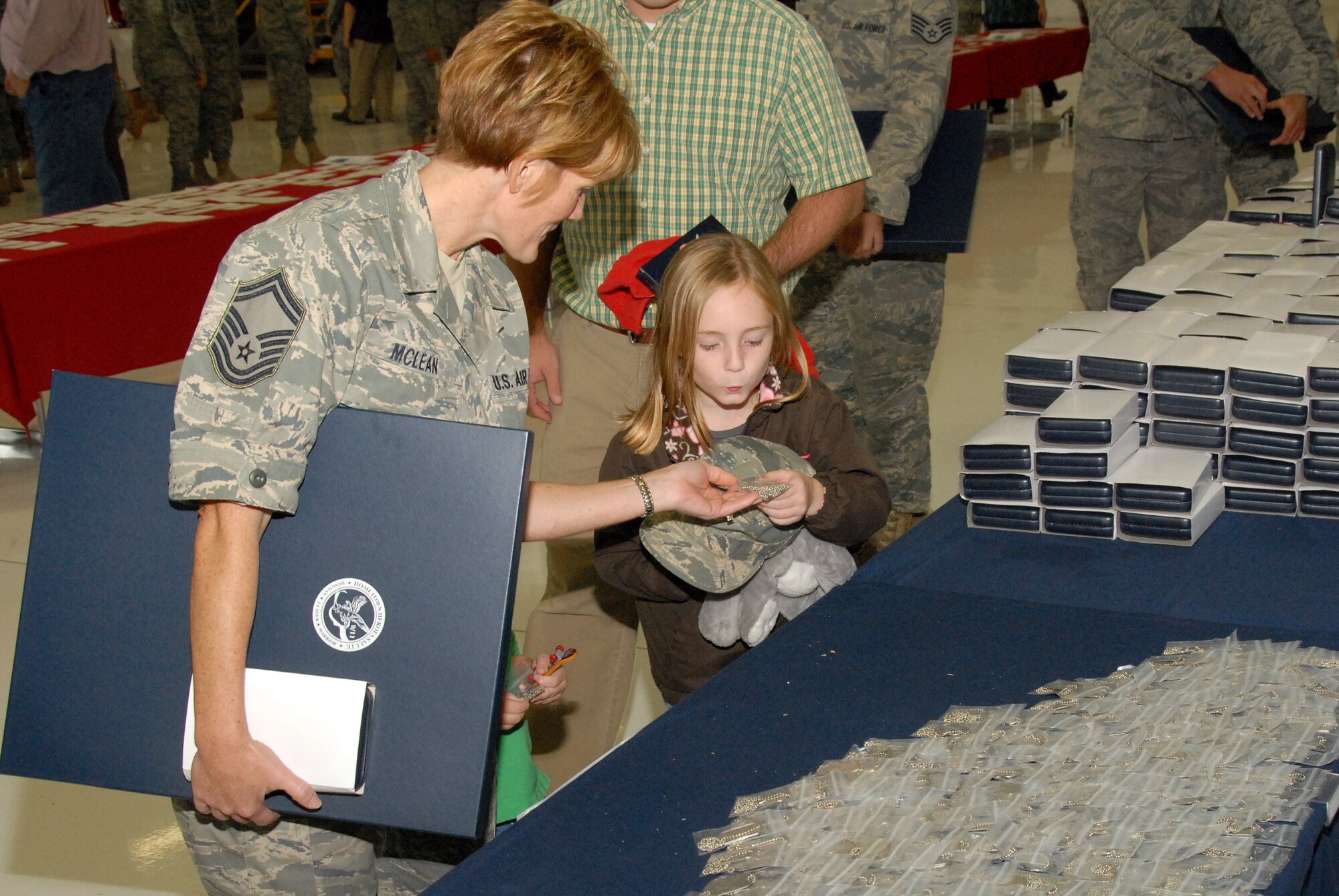 Senior Master Sgt. Sheri Mclean, 115th Fighter Wing, presents her daughter a set of Hometown Heroes Salute commemorative dog tags as a token of the National Guard's appreciation at a recent Hometown Heroes Salute ceremony at Truax Field in Madison, Wis. The ceremony included more than 350 members of the 115th Fighter Wing at the unit's first-ever Hometown Heroes Salute ceremony.  The National Guard program honors recognizes Airmen who deployed for more than 30 consecutive days for Operations Noble Eagle, Enduring Freedom and Iraqi Freedom and all other contingency operations.  Airman's families and centers of influence were also recognized. (U.S. Air Force photo by Tech. Sgt. Ashley Bell)