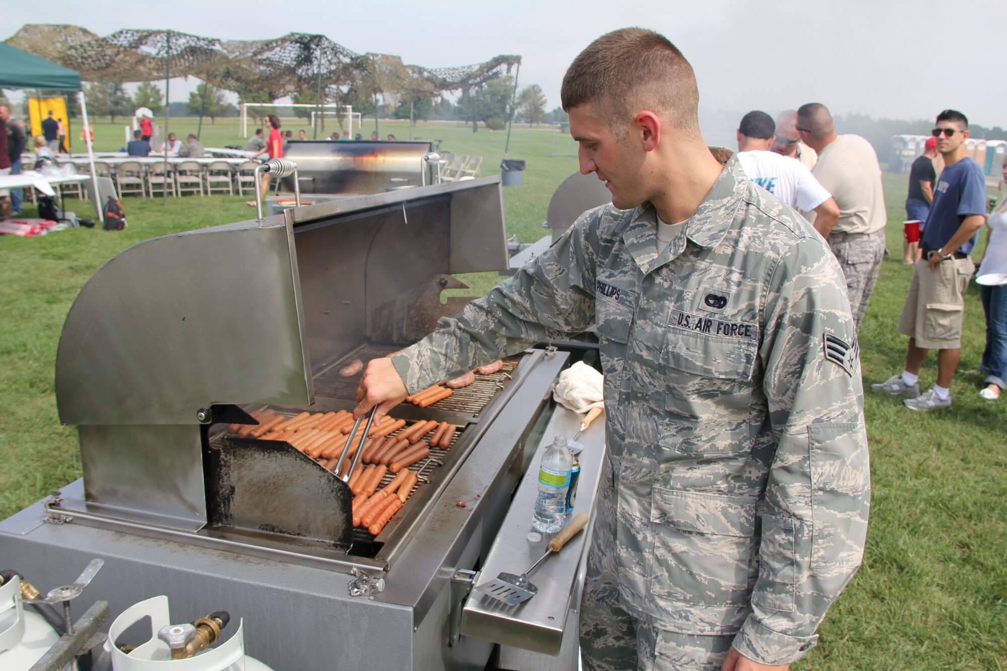 Senior Airman Jacob Phillips helps cook dozens of hot dogs and burgers at the annual 932nd Airlift Wing Picnic.  The event brings Reservists and their families together for a day of food, fun and games.  Airman Phillips is assigned to the 932nd Maintenance Squadron, whose members did the set-up and all the cooking. (U.S. Air Force photo/Tech. Sgt. Dan Oliver)