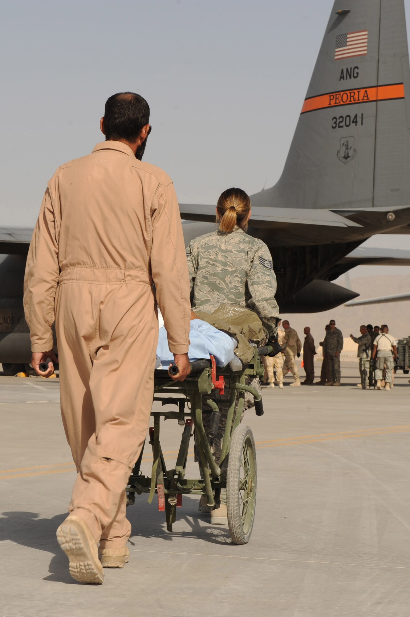 Sgt. Sur Gulap and Staff Sgt. Christina Vanderpool transport an injured patient to a waiting C-130H Hercules, operated by a West Virginia Air National Guard aircrew based out of the 455th Expeditionary Aeromedical Evacuation Flight at Bagram Airfield, Afghanistan, Sept. 12, 2010, at Kandahar Airfield, Afghanistan.  Sergeant Gulap is a flight medic with the Afghan Air Force, Kandahar Air Wing Medical Group and Sergeant Vanderpool is with the 451st Expeditionary Aeromedical Evacuation Squadron Staging Facility.  (U.S. Air Force photo by Tech. Sgt. Chad Chisholm/Released)