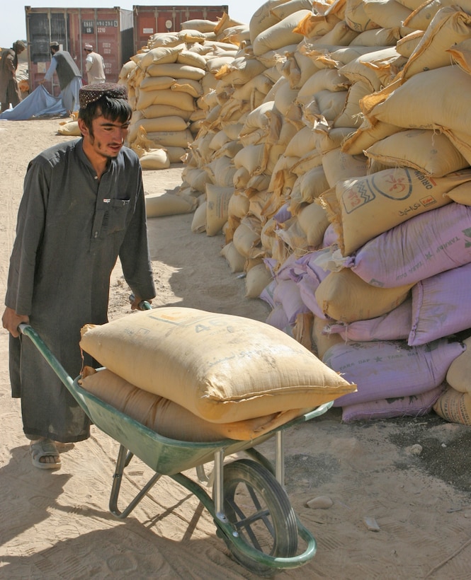 An Afghan farmer wheels a load of fertilizer out to his truck during the fall seed distribution program in Helmand Province. Marines and sailors with 2nd Battalion, 9th Marines began the distribution of seeds and fertilizers to Afghan farmers Sept 20, preparing locals for the upcoming planting season.