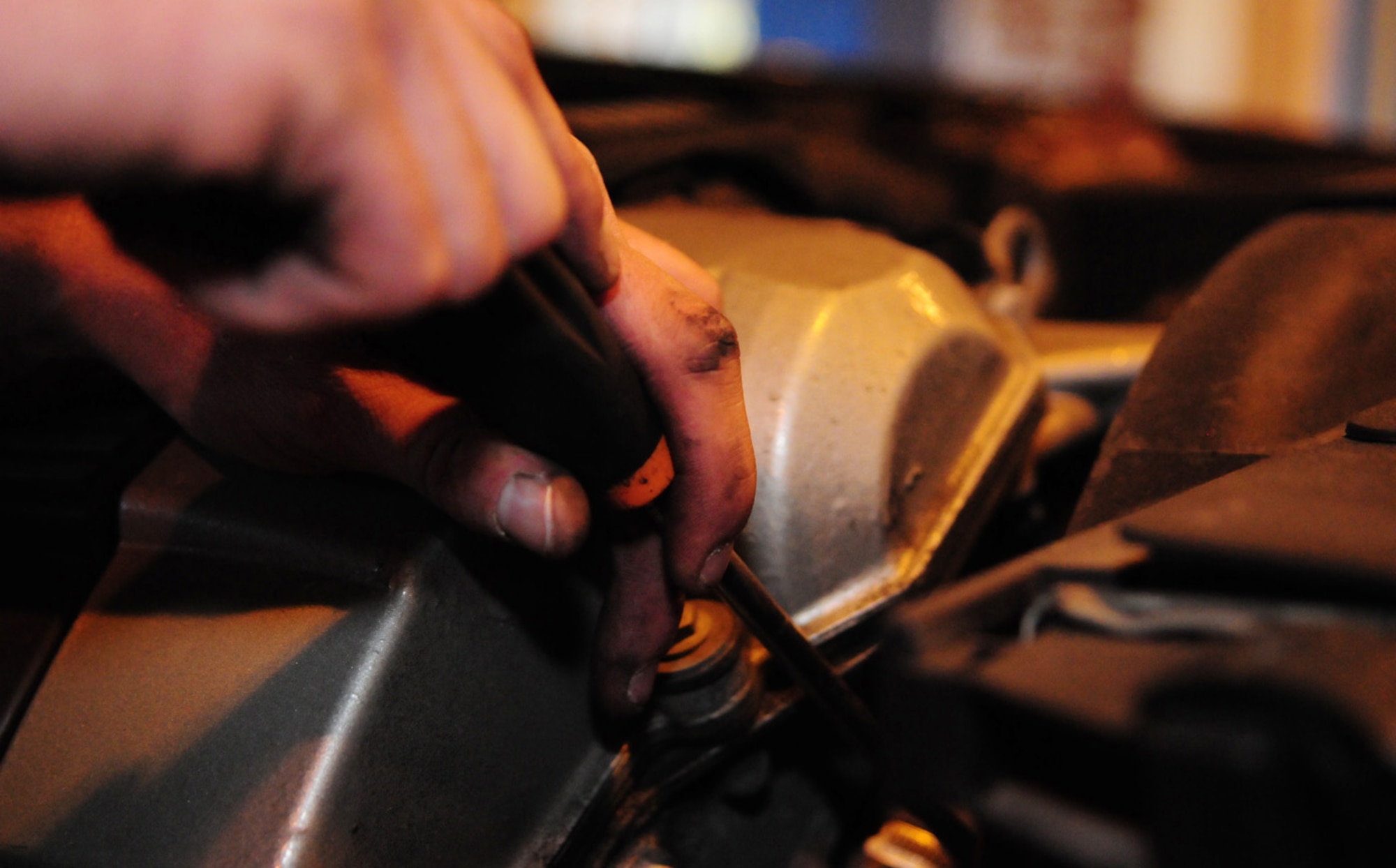 RAF MILDENHALL, England -- A mechanic unscrews an engine cover so he can inspect the spark plugs on a customer's car Sept. 17 at the auto hobby shop here. (U.S. Air Force photo/Karen Abeyasekere)