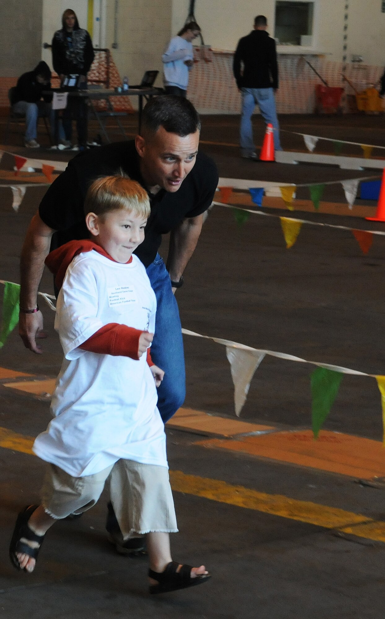 RAF MILDENHALL, England -- A Joan Mann Special Sports Day participant (front) runs with Lt. Col. Wayne Mattingly, 100th Communications Squadron commander, at Hangar 711 Sept. 18. The sports day was designed to allow special-needs athletes to compete in a fun atmosphere. This was the 29th year RAF Mildenhall has hosted the event. (U.S. Air Force photo/Staff Sgt. Thomas Trower) 