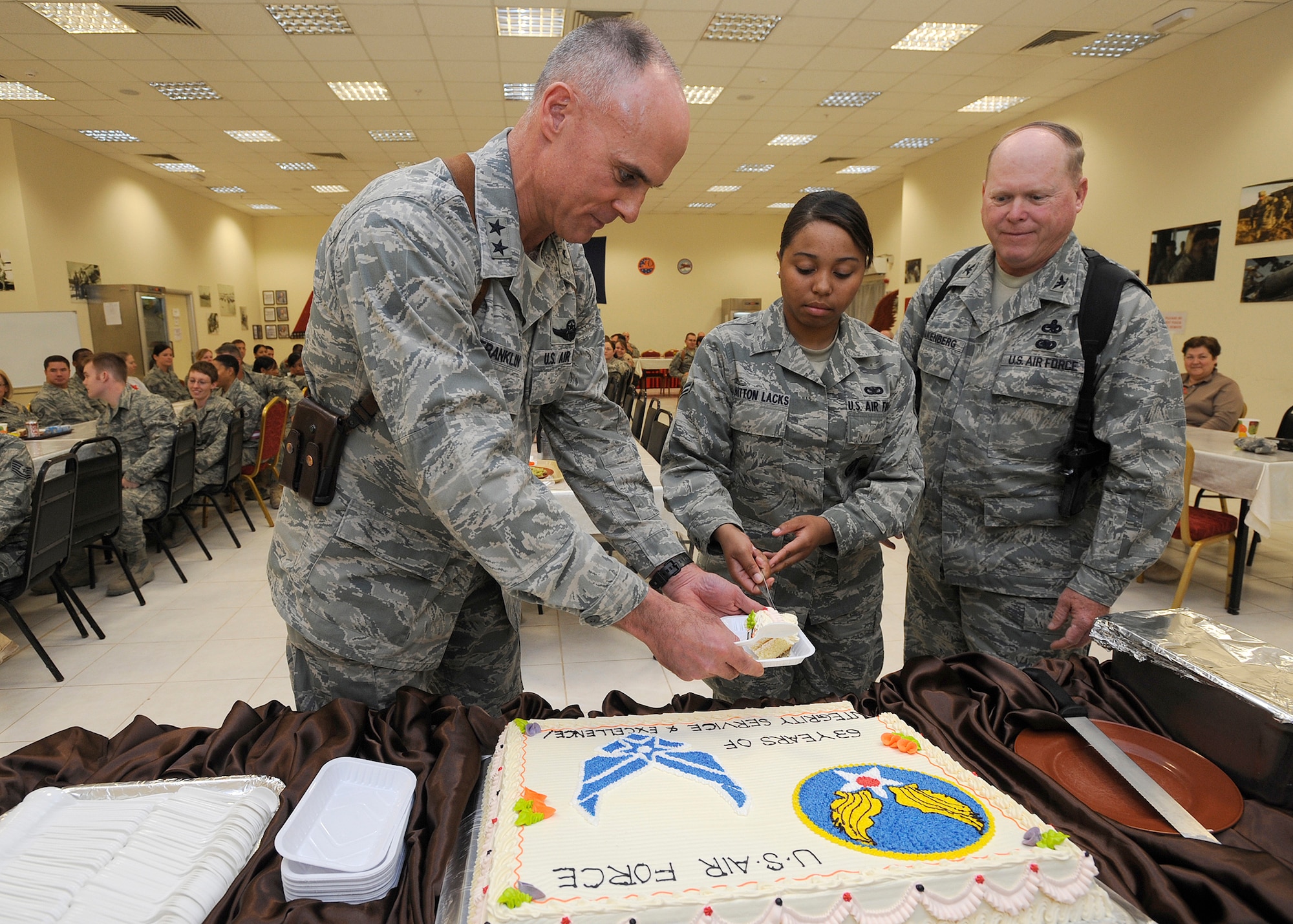 Maj. Gen. Craig Franklin, 332nd Air Expeditionary Wing commander, receives the first piece of the Air Force birthday cake as the guest of honor from the youngest Airman, Airman 1st Class Kierra Britton-Lacks, 532nd Expeditionary Security Forces Squadron, and the wisest Airman, Col. David Snakenberg, 332nd Air Expeditionary Wing director of staff Sept. 18, 2010, at Joint Base Balad, Iraq. More than 80 servicemembers came together to celebrate 63 years of the heritage and airpower of the United States Air Force. (U.S. Air Force photo/ Senior Airman Matt Coleman-Foster)