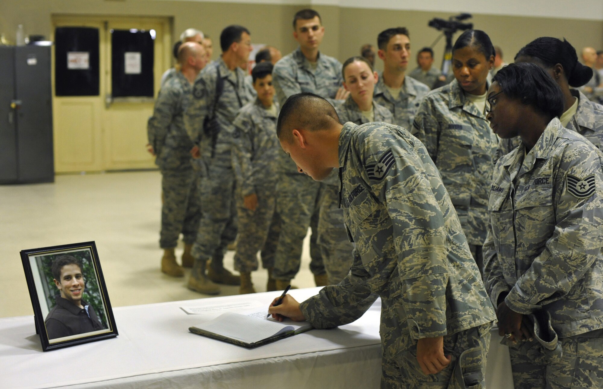 Servicemembers sign a condolences book prior to a memorial service for Senior Airman James Hansen Sept. 19, 2010 at Joint Base Balad, Iraq.  Airman Hansen, 25, an airfield operations manager assigned to the 332nd Expeditionary Operations Support Squadron, died in an explosive ordnance disposal accident here Sept. 15.  The ceremony included the reading of the citation for the Air Force Commendation Medal for Airman Hansen's exemplary service during his deployment from the 46th Operations Support Squadron, Eglin Air Force Base, Fla., in support of Operation Iraqi Freedom and Operation New Dawn. (U.S. Air Force photo/Lt. Col. Robert Couse-Baker)
