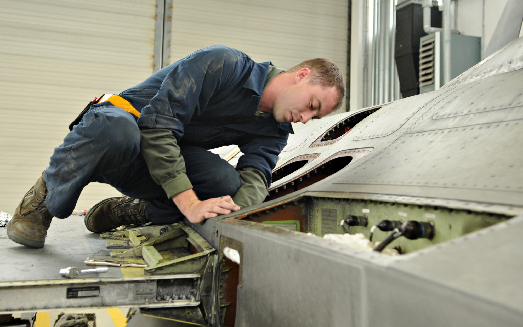 SPANGDAHLEM AIR BASE, Germany – Senior Airman Malcom Asher, 52nd Component Maintenance Squadron aircraft fuel systems journeyman, fastens bolts to the wing of an F-16 Fighting Falcon from inside the fuselage Sept. 16. The wing of the F-16 was removed to replace an internal bracket that had a minor stress fracture. (U.S. Air Force photo/Staff Sgt. Benjamin Wilson)
