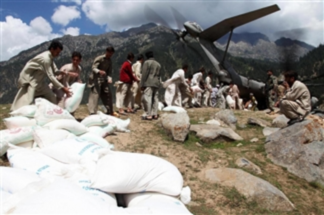 Local men assist U.S. Marines in offloading hundreds of bags of flour from a KC-130J Super Hercules aircraft at Gilgit Air Base, Pakistan, on Sept. 8, 2010.  