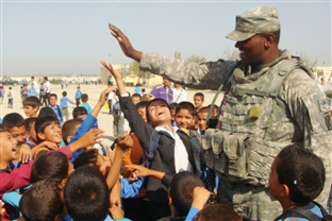 A U.S. Army soldier plays “High Five” with a group of children at a school in the Northern Afghanistan border town of Hairatan. The soldier is assigned to the 10th Mountain Division‘s Company A, 1st Brigade Special Troops Battalion, 1st Brigade Combat Team. The unit's soldiers are helping improve schools in the area.