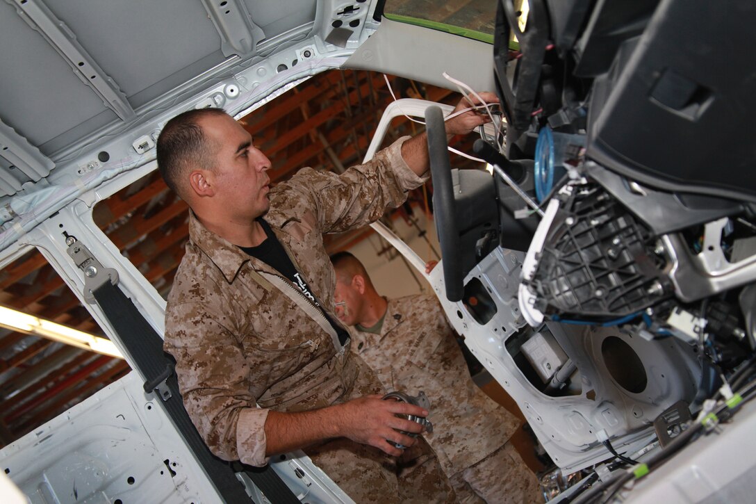 Staff Sgt. Rodrigo Gonzales, the range control supervisor of BEARMAT range control unit, checks wiring and interior parts Wednesday at the Combat Center's Auto Skills Center. Gonzales is part of Kai Hei Tai, the installation's team in the Scion Battle of the Builds.