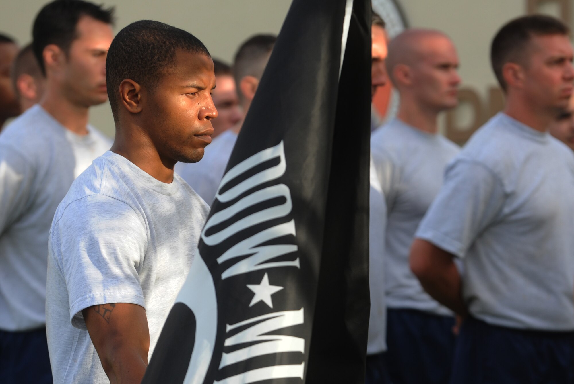 Senior Airman Jamelle Dalton, 25th Air Support Operations Squadron Tactical Air Control Party, holds the POW/MIA flag as his unit stands in formation for a reveille and wreath-laying ceremony Sept. 17 at Joint Base Pearl Harbor-Hickam, Hawaii, to honor those 81,864 who are prisoners of war or missing in action. (U.S. Air Force photo/Staff Sgt. Carolyn Viss)