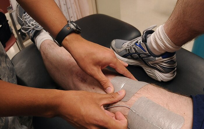 NELLIS AIR FORCE BASE, Nev.--  Senior Airman Joseph Suarez, 99th Medical Operation Squadron physical therapy journeyman, connects Master Sgt. Jeramie Brown, 99th Air Base Wing broadcast journalist, to an electrical stimulation machine Sept 21.  (U.S Air Force Photo / Senior Airman Stephanie Rubi)