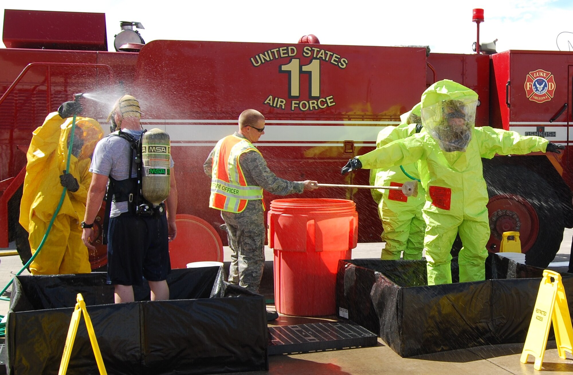 LUKE AIR FORCE BASE, Ariz. -- Members of the 944th Fighter Wing Emergency Management and Readiness Flight completed an in-house Hazardous Material certification program provided by the 944 FW Fire Department Sept. 12 here. Master Sgt. Charles Tehan (right), 944th Civil Engineer Squadron Readiness NCO-in-charge, and Senior Airman Nathan Tracy (left), Emergency Management Journeyman, processed through full decontamination procedures after exiting a simulated contaminated site containing hazardous material. This exercise was the capstone to a four-day training and certification program consisting of written and hands-on tests. Upon completion 944th FW EM Airmen are level 2 certified and ready to respond to HAZMAT incidents. (U.S. Air Force photo/Capt. David Caraway)