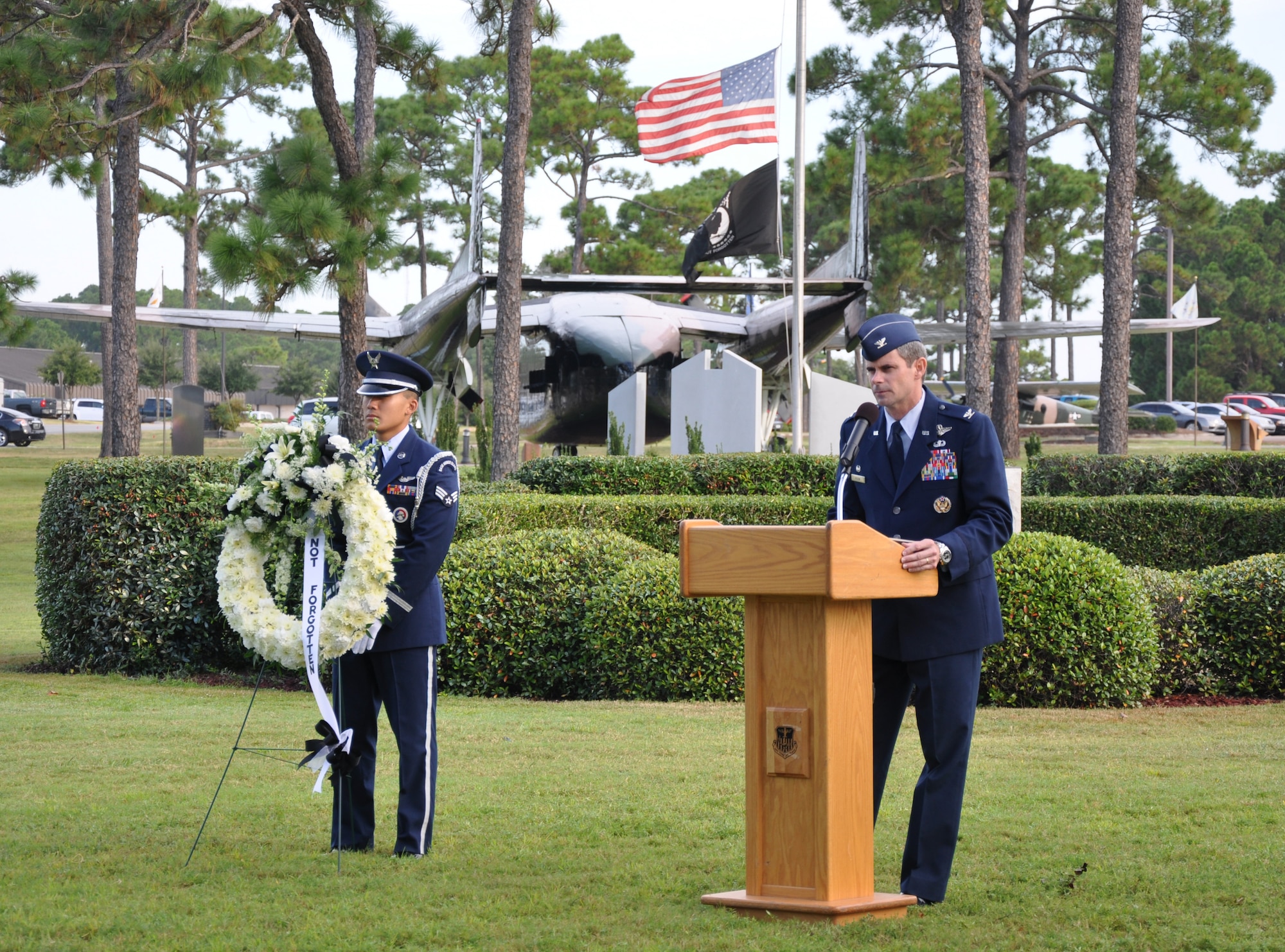 Col. Michael Plehn, 1st Special Operations Wing commander, speaks to an audience as Senior Airman Thirasack Bone, 1st SOW Honor Guard, stands behind a memorial wreath during a remembrance ceremony at the Airpark at Hurlburt Field, Fla., Sept. 17, 2010. The base held the event along with other military installations, schools and veteran’s halls across the country in observance of National POW/MIA Recognition Day.  (DoD photo by U.S. Air Force Airman 1st Class Joe McFadden) (RELEASED)