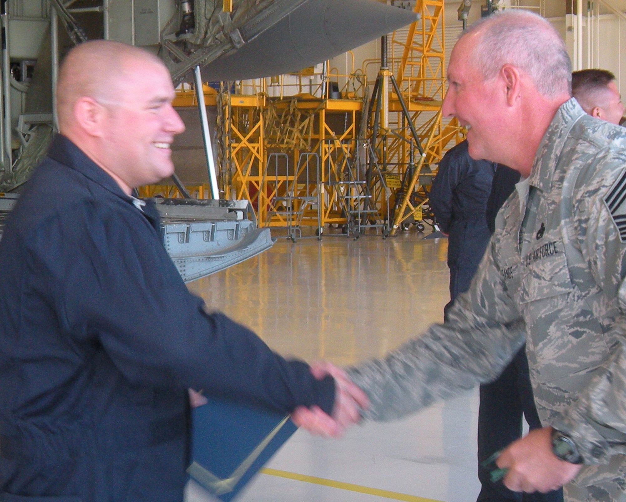 Staff Sgt. Gregg Rusmanis, 52nd Airlift Squadron dedicated crew chief, shakes hands with Chief Master Sgt. Michael Sands Aug. 8 at Peterson Air Force Base, Colo. Sergeant Rusmanis was one of 24 Air Force Reserve and Active Duty C-130 Hercules maintainers who were named "dedicated crew chiefs" to their respective aircraft. Dedicated crew chiefs provide additional continuity and streamline processes for maintaining the Air Force's fleet of C-130 aircraft. Chief Sands is the 302nd Aircraft Maintenance Squadron superintendent. (U.S. Air Force photo/Staff Sgt. Jenni Deylius)