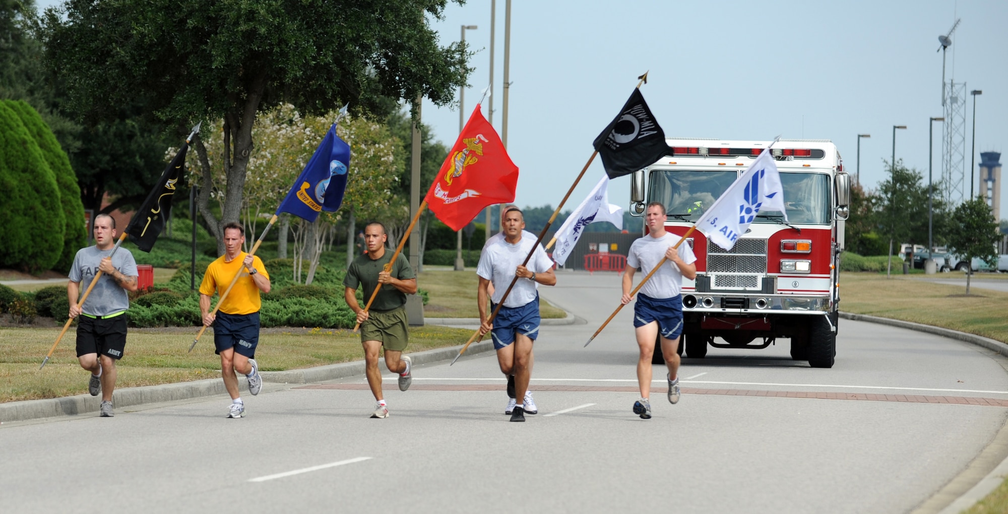 Members from each military branch run their respective flags while led by the Prisoner of War/Missing in Action flag to the base parade grounds for the start of the POW/MIA retreat ceremony on Joint Base Charleston, S.C., Sept. 17, 2010. A series of teams held a running vigil at the base track, circling it for 24 hours. For the final portion of the run, a joint-service team was followed by a fire truck and two patrol cars as they ran down Hill Boulevard to the base parade grounds. (U.S. Air Force photo/Senior Airman Timothy Taylor)
