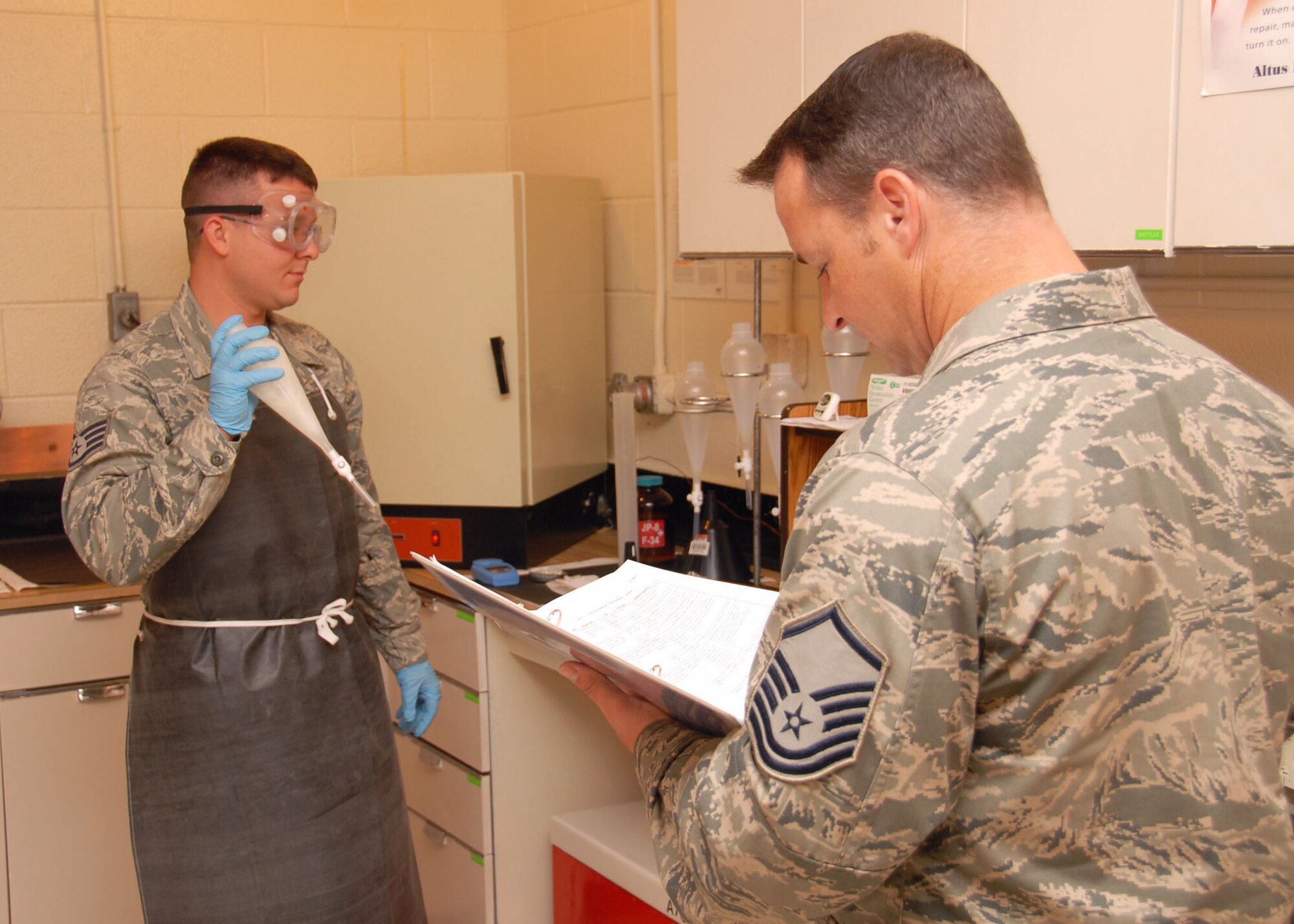 ALTUS AIR FORCE BASE, Okla. – (L) Staff Sgt. Michael Poulin, from the 97th Logistics Readiness Squadron, performs a test to determine the concentration of Glycol Monomethyl Ether in the jet fuel sample under the eyes of the Logistics Compliance Assessment Program inspector Master Sgt.  Jason Leslie at fuels laboratory September 15. The 97th (LRS) had (LCAP) inspections Sept. 13-17 to make sure the squadron was up to standards in all areas. (U.S. Air Force photo by Airman 1st Class Christopher Arnold/Released 97th Air Mobility Wing – Public Affairs)